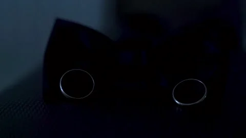 Two wedding rings lie on the bow tie and illuminated by a bright beam of light. Stock Footage 221017576