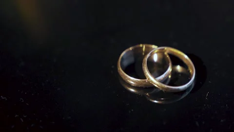 Two wedding rings lie on the table and illuminated by a bright beam of light. Stock Footage 221468382