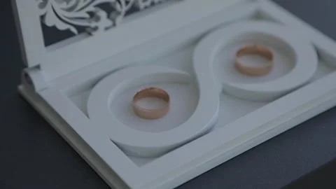Two wedding rings lying in a white wooden box with an infinity symbol. Stock Footage 322020467