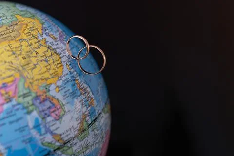 Two wedding rings placed on a globe Stock Photos