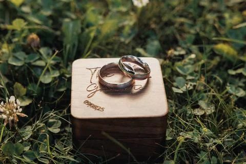 Two wedding rings rest gently on a carved wooden box 스톡 사진
