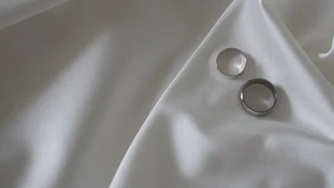 Two wedding rings rest on a white surface, captured in macro photography 库存影片 267881204