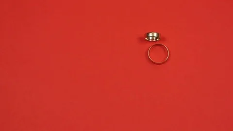Two wedding rings roll on a red background and clash. Slow motion Stock Footage 77010988