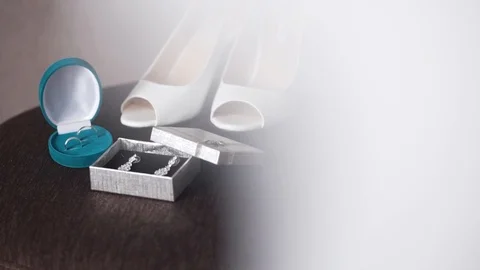 Two wedding rings rolling together near bride's wedding shoes Video stock 95780815