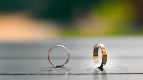 Two wedding rings standing together on a wooden surface, The image reinforces Stock Footage 281190305