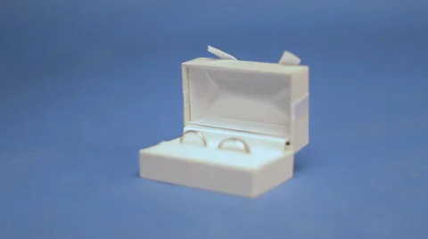 Two wedding rings in the white box on the blue screen Stock Footage 33615723