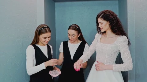 Two wedding salon consultants help the bride try on a wedding dress. The Vidéo 199851860