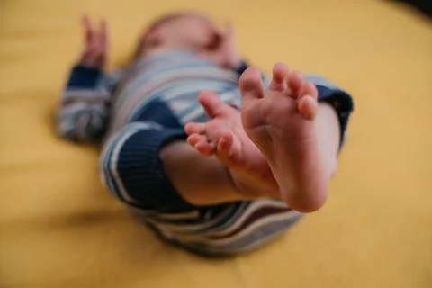 Two week old very cute baby in overalls on an orange plaid Foto stock