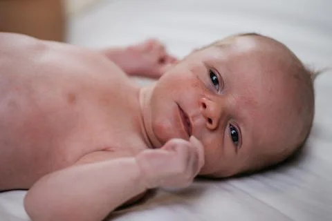 Two week old very cute baby naked on a white sheet Stock Photos