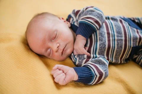 Two week old very cute baby in overalls on an orange plaid Stock Photos