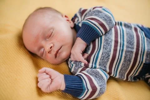 Two week old very cute baby in overalls on an orange plaid Stock Photos