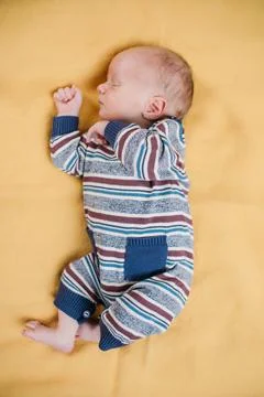 Two week old very cute baby in overalls on an orange plaid Stock Photos
