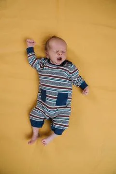 Two week old very cute baby in overalls on an orange plaid Stock Photos