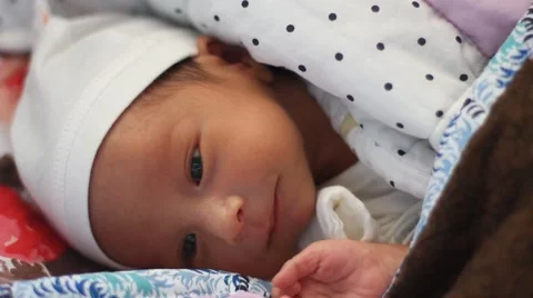 Two weeks old cute baby lying on bed peacefully with his eyes open Stock Footage 55437655