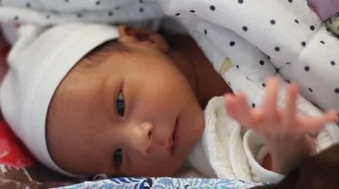 Two weeks old cute baby lying on bed peacefully with his eyes open Stock Footage 55456129