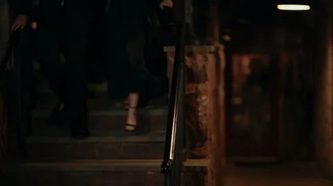 Two well-dressed couples walk down staircase to party Stock Footage 42892075