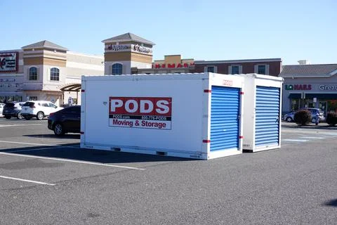 Two white and blue storage pods seen in the parking lot of a shopping center Stock Photos
