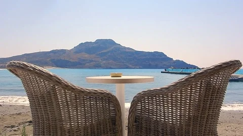 Two white armchair and a table with blue sea and some mountains in background. Stock-Footage 79853644