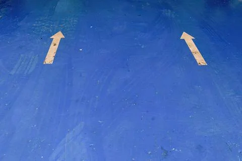 Two white arrows  and some tire tracks on the blue floor of a car workshop, i Stock Photos