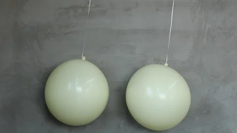 Two white balloons Against Gray Wall Stock Footage 95967592