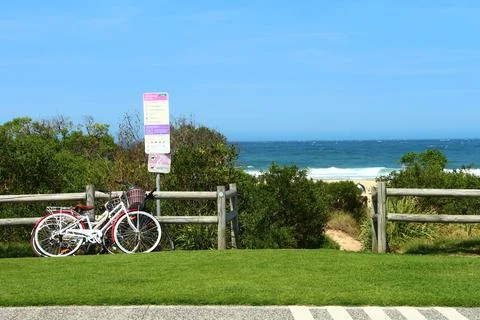 Two White Bicycles Parked At A Beachside Fence Overlooking The Ocean Stock Photos