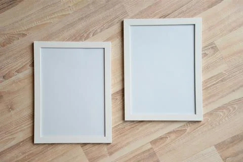 Two white blank frames on the wooden background. Mockup concept. Stock Photos