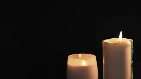 Two white burning candles are isolated on a black background. The concept of Stock Footage 124980312
