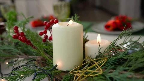 Two white burning candles on the table between spruce branches and spices in Stock Footage 292677423