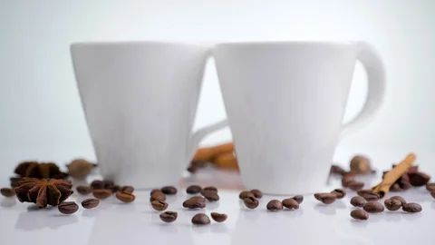 Two white ceramic cup with coffee beans, star anise and cinnamon sticks Stock Footage 129363876