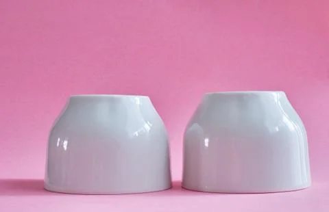 Two white ceramic cups without handles on pink background Stock Photos