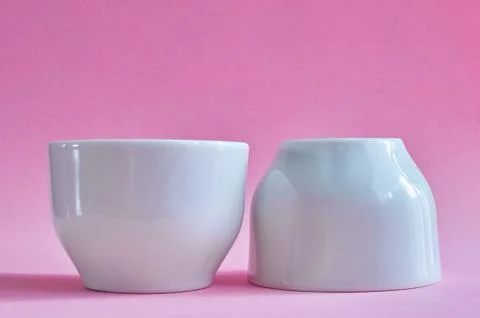 Two white ceramic cups without handles on pink background Stock Photos