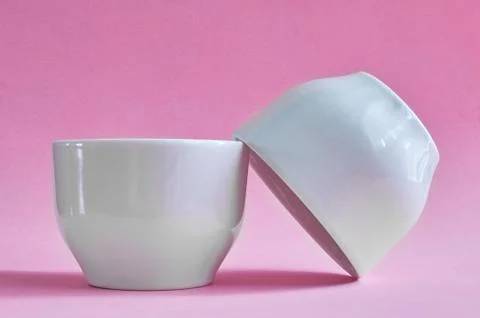 Two white ceramic cups without handles on pink background Stock Photos