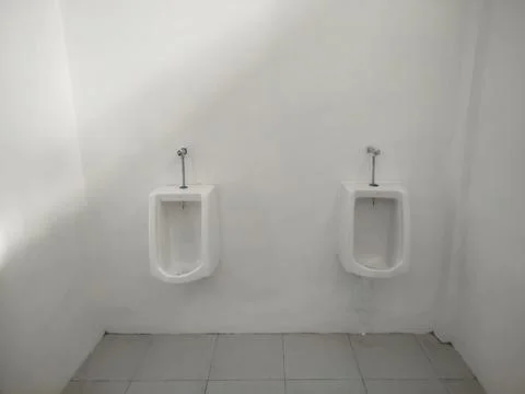 Two White Ceramic Wall-Mounted Urinals in Public Restroom with Geometric Sh.. Stock Photos