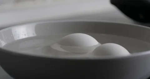 Two White Chicken Hard Boiled Eggs Are Cooled In A Plate With Cold Water Stock Footage 127754997