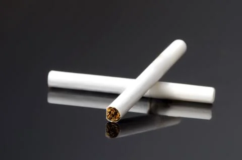 Two white cigarettes with reflection on black background. Stock Photos