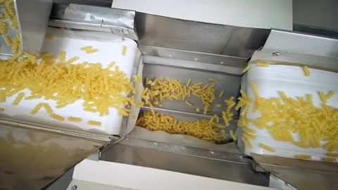 Two white conveyor belts move raw pasta to another one wave shaped conveyor Stock Footage 163255472