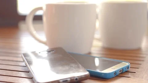 Two white cups are on the table in the cafe. next to it there are two telephones Stock Footage 90421704