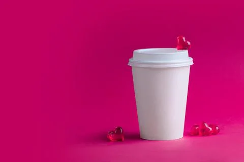 Two white cups for coffee and tea and glass hearts on a pink background. Stock Photos