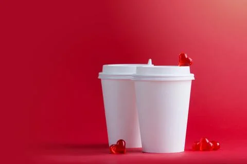 Two white cups for coffee and tea stand next to glass hearts Stock Photos