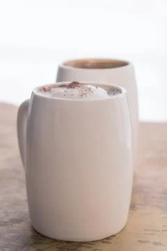 Two white cups of coffee stand on a world map against a light background Stock Photos