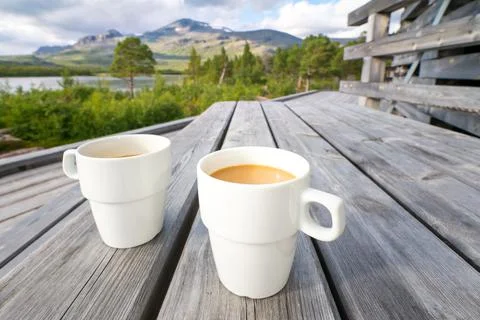 Two white cups filled with coffee with milk on a wooden table with arctic Stock Photos