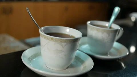 Two white cups of hot tea stand on the table, with a beautiful curly steam Stock Footage 123417224