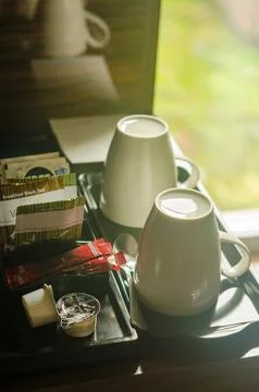 Two white cups, some tea bags and coffee on the coffee table in hotel room Stock Photos