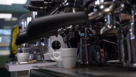 Two white cups into which black coffee is poured from large metal coffee machine Stock Footage 124415702