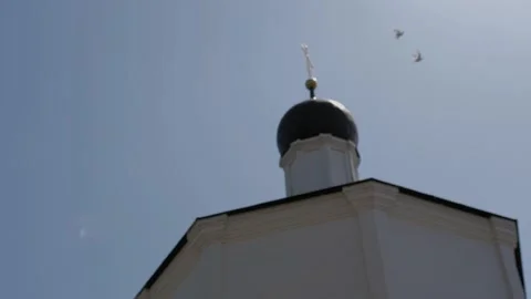Two white doves fly near dome of the Orthodox Church. They go off in the bokeh. Stock Footage 132099065