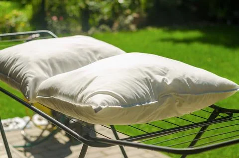 Two white down pillows are dried or ventilated in an open air in the garden. Stock Photos