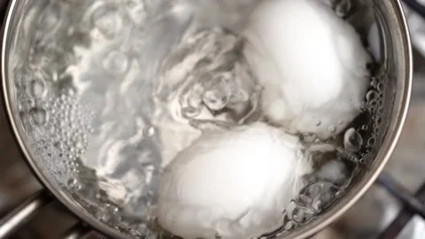 Two white eggs are boiled in a saucepan. Slow motion. Stock Footage 156395960