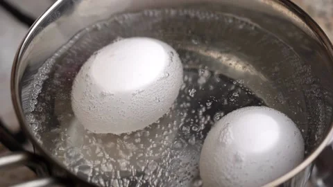 Two white eggs are boiled in pot of water. Beginning of boil. 스톡 동영상 156420358