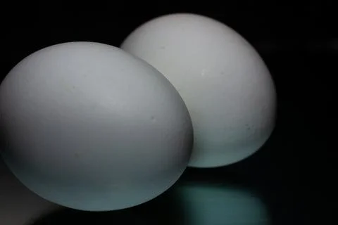 Two white eggs are reflected on a black background Stock Photos
