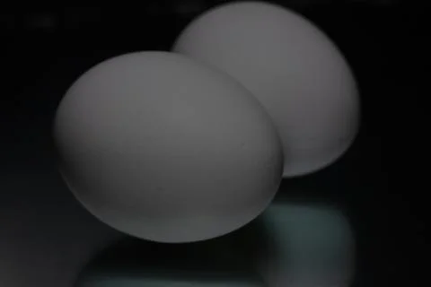 Two white eggs are reflected on a black background Stock Photos